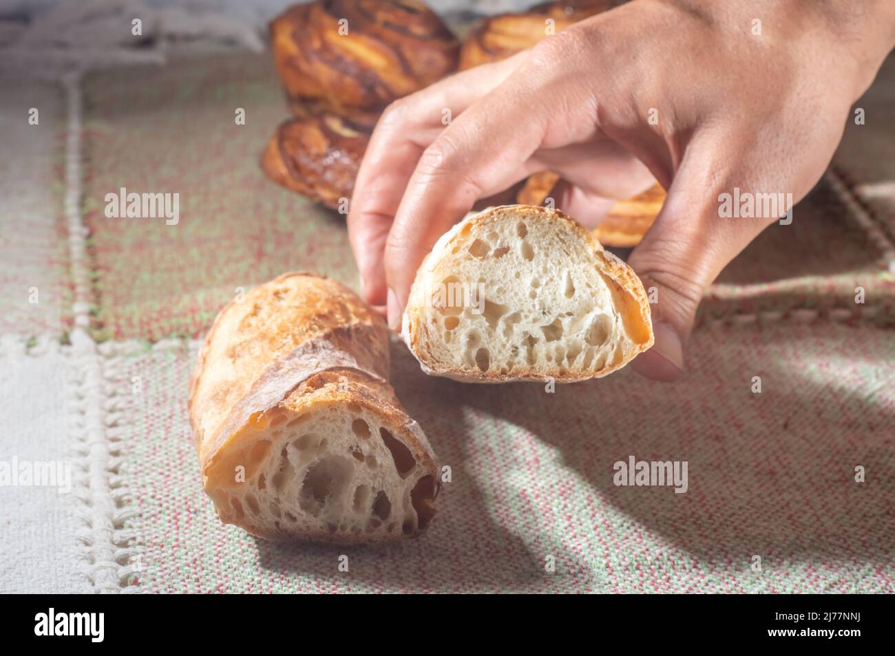 Pan hecho a mano sobre una mesa con las manos, luz suave. Foto de stock
