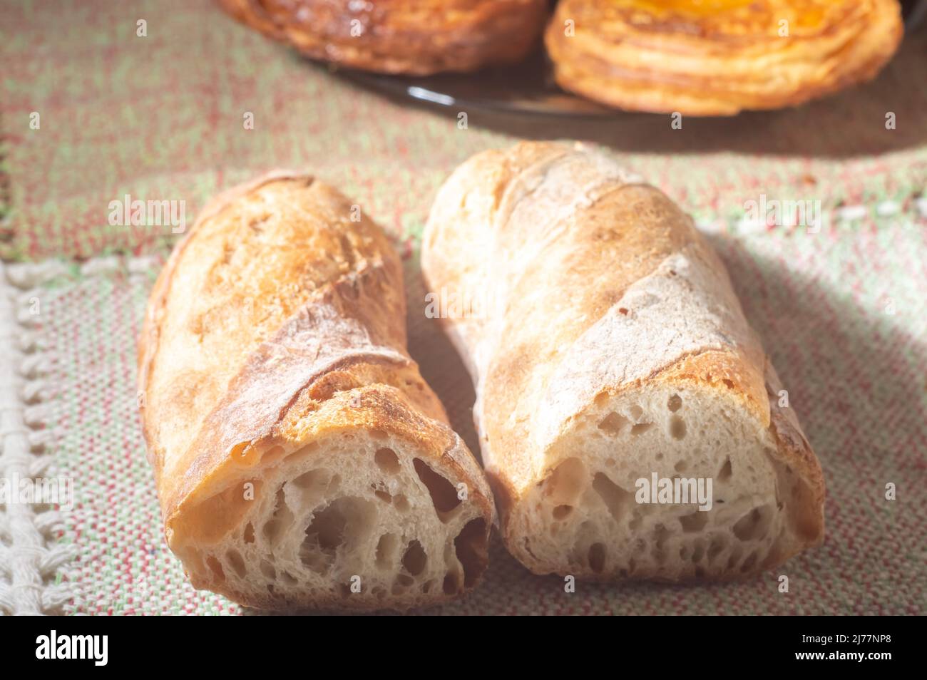 Pan hecho a mano sobre una mesa con las manos, luz suave. Foto de stock