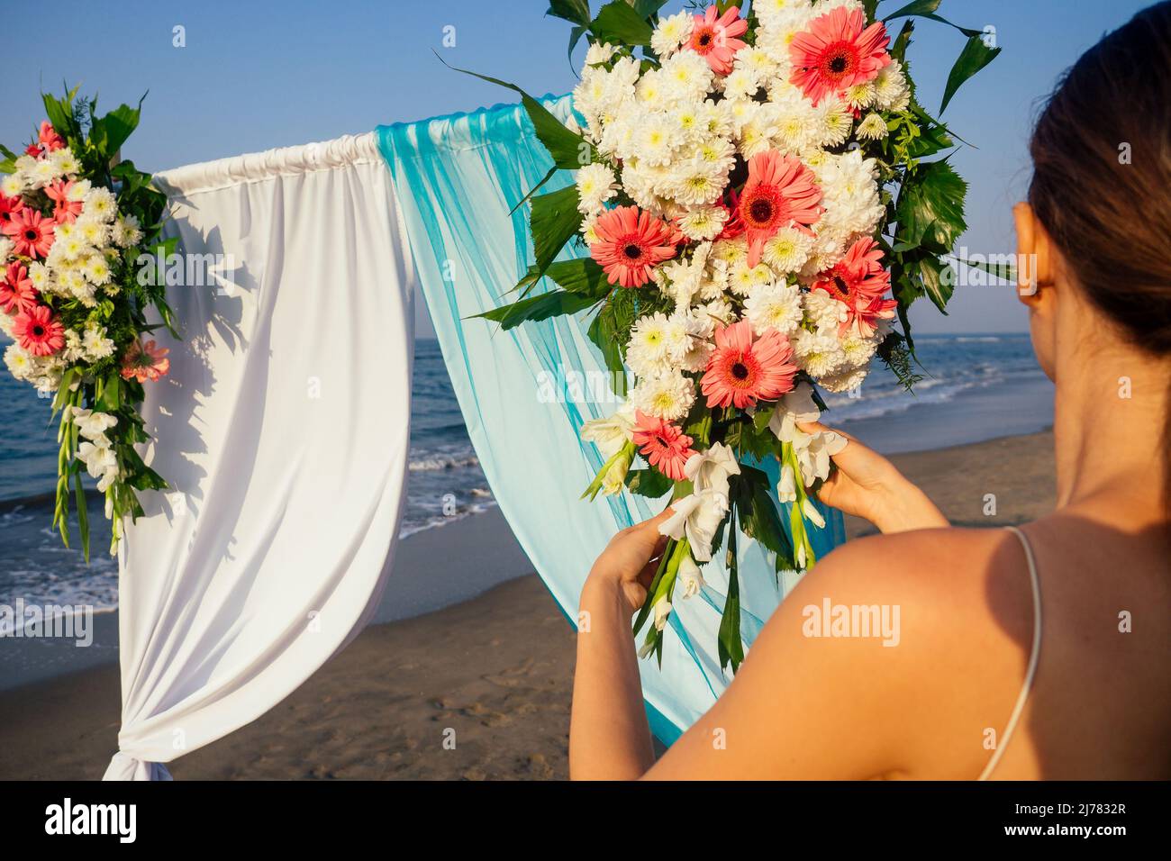Decorador trabajando con la composición de flores para el arco de la boda  en la playa del océano Fotografía de stock - Alamy