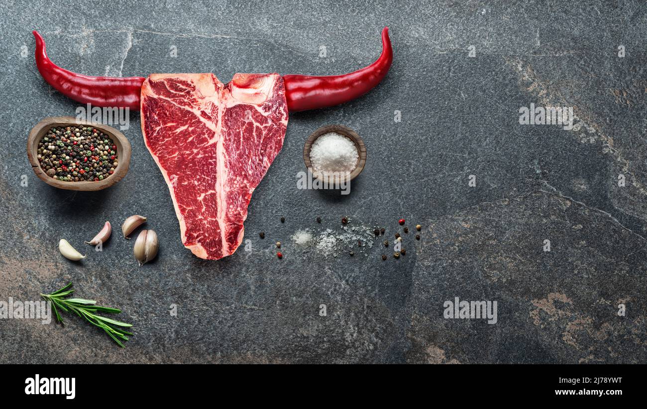 Filete de ternera en forma de hueso T y pimientos calientes dispuestos en forma de cabeza de toro. Panorama conceptual de los alimentos. Foto de stock