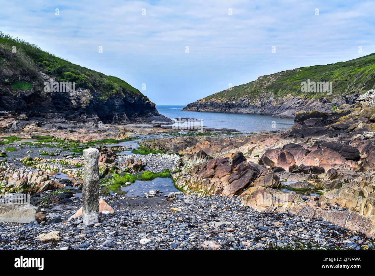 Playa de Port Quin en la costa norte de Cornwall, tomada en aguas bajas exponiendo las muchas rocas y cuevas. Foto de stock