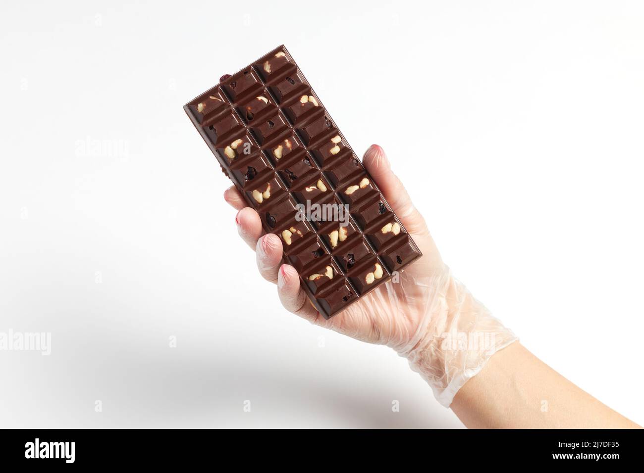 Apetitoso bar de chocolate con relleno de frutos secos en la mano del confitero Foto de stock