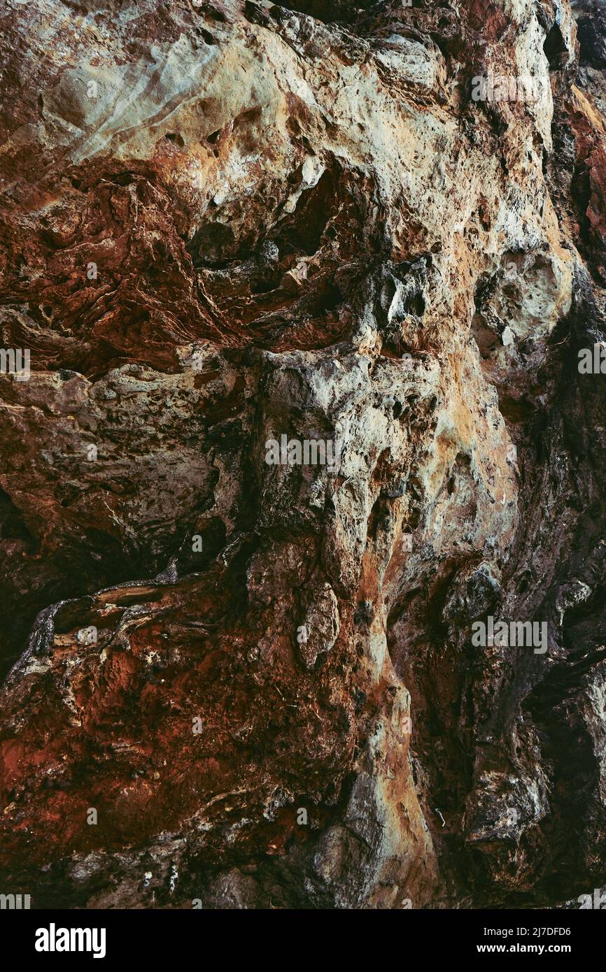 Pared de piedra marrón-negra de la cueva como fondo o como telón de fondo. Imagen vertical Foto de stock