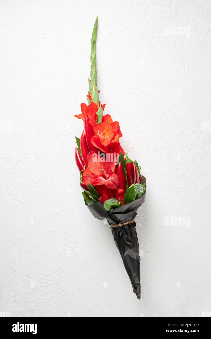 Ramo de gladioluses rojos, pimiento rojo, decorado con hojas de laurel y brócoli sobre fondo blanco Foto de stock