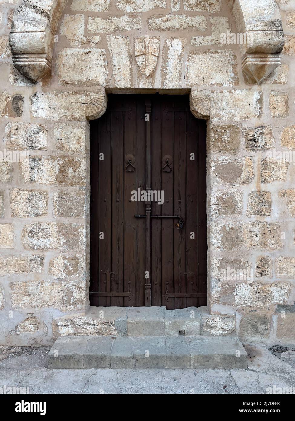 Antigua puerta de madera marrón con un enorme equipo de bloqueo en una pared de piedra Foto de stock