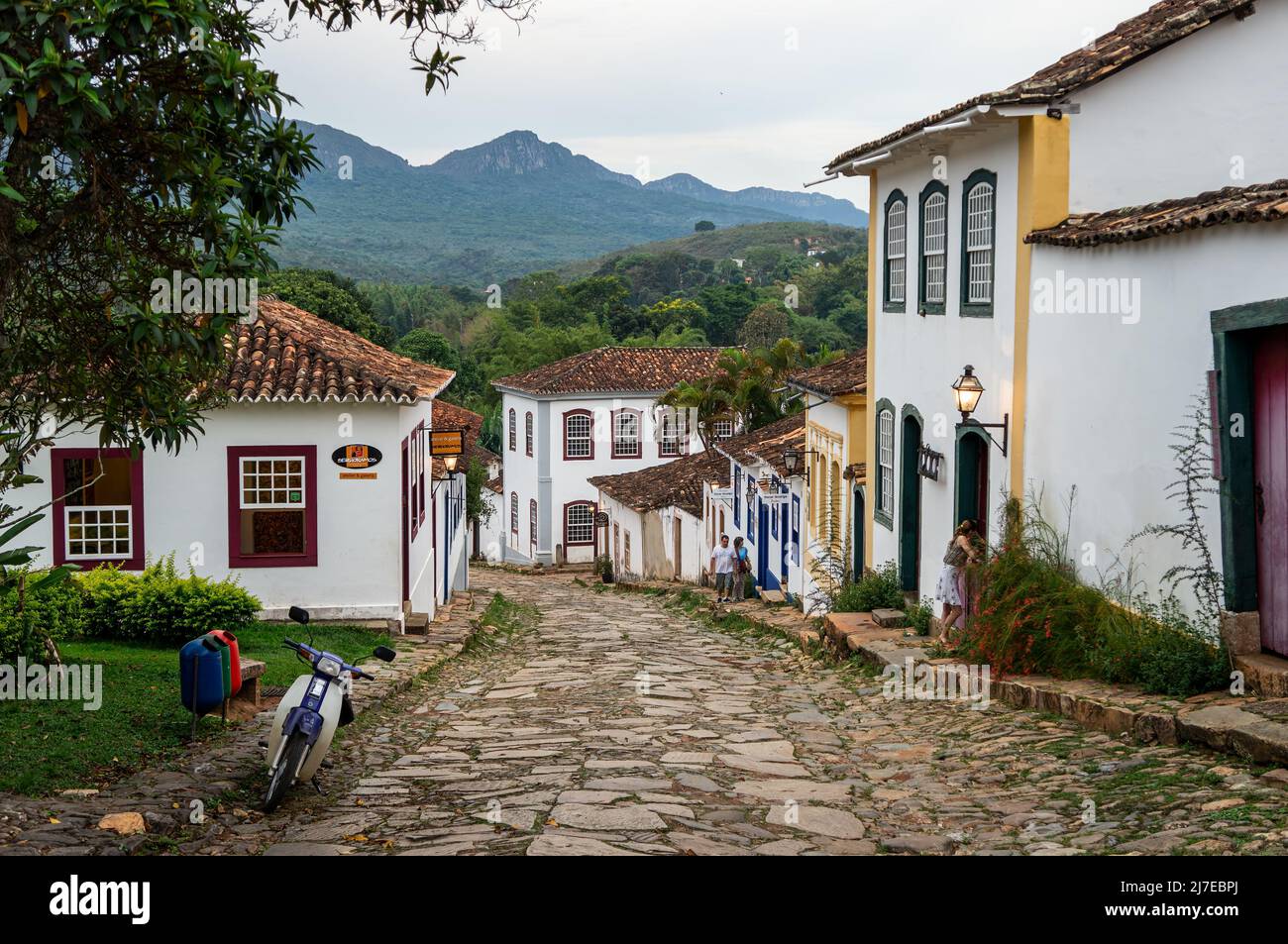 Vista de la calle empinada Rua da Camara con muchas casas coloniales a ambos lados bajo el cielo nublado en el centro histórico de Tiradentes. Foto de stock