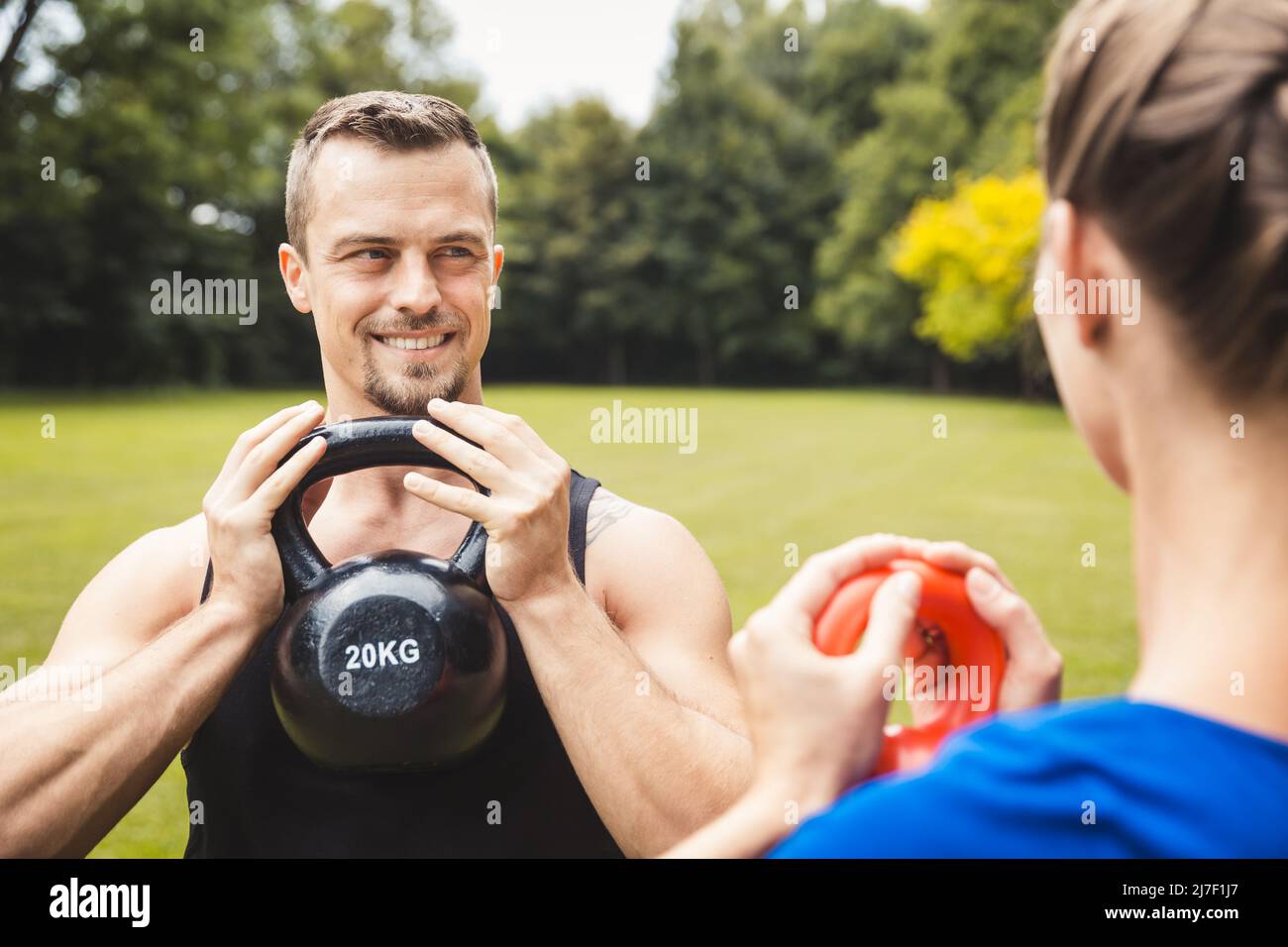 Feliz hombre haciendo ejercicio en el parque con entrenador Foto de stock