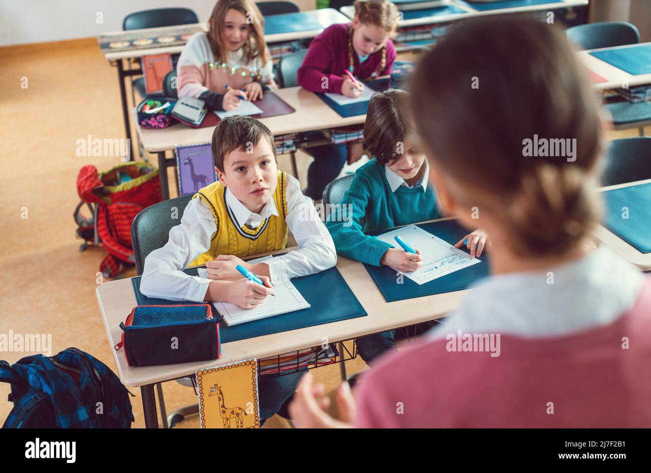 Alumnos, niños y niñas, en clase escuchando al profesor de la escuela Foto de stock