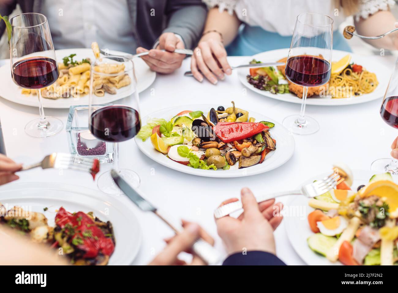 Cuatro amigos comiendo comida italiana en un restaurante de lujo, cerca Foto de stock
