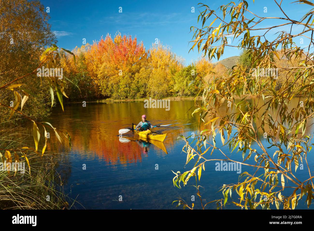 Kayak y reflexiones otoñales en Kellands Pond, cerca de Twizel, Mackenzie District, North Otago, South Island, Nueva Zelanda (lanzamiento del modelo) Foto de stock