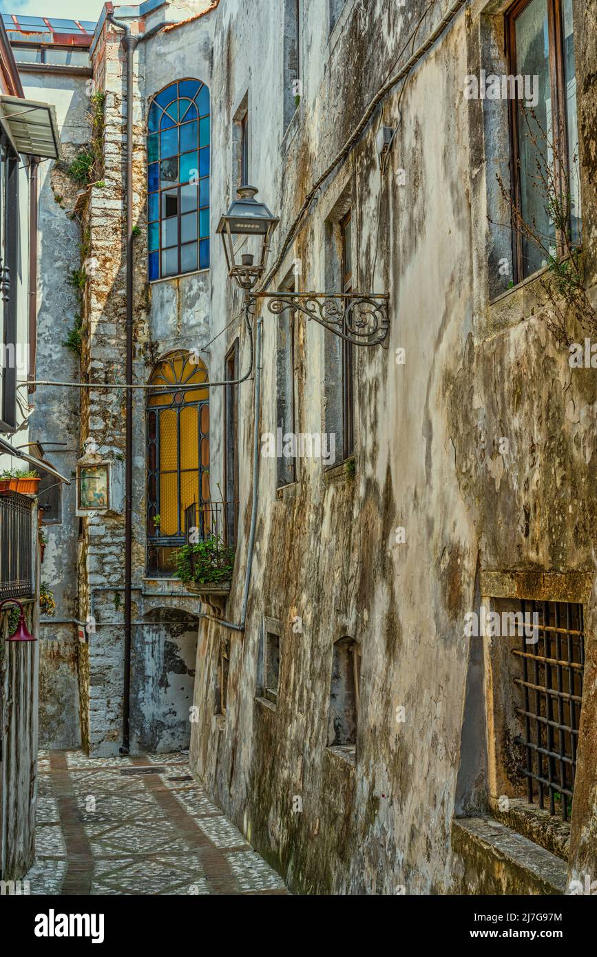 Característico callejón estrecho entre edificios altos con vidrieras de color naranja y azul. Vico del Gargano, provincia de Foggia, Puglia, Italia Foto de stock
