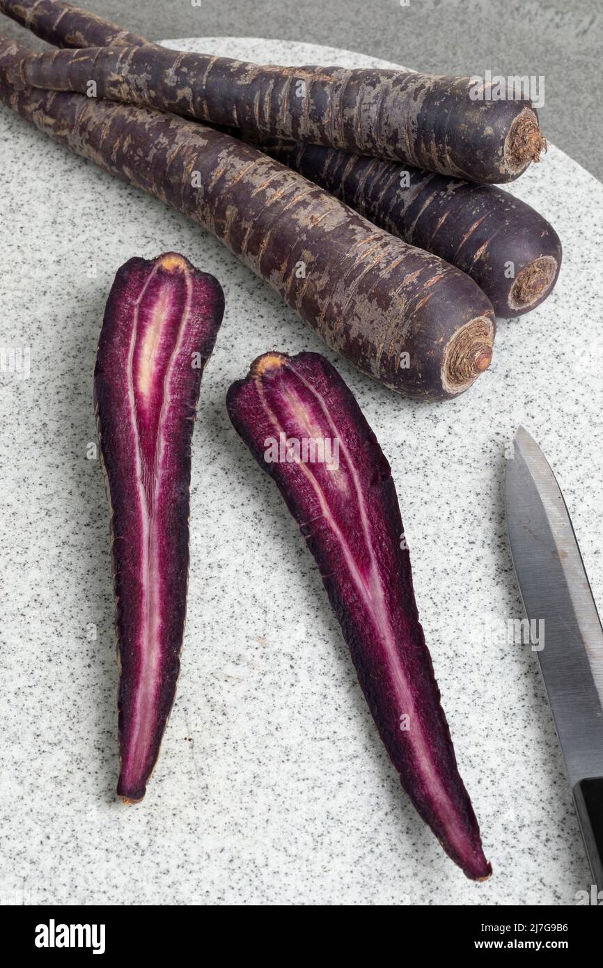 Zanahoria púrpura y rodajas en una tabla de cortar de cerca Foto de stock