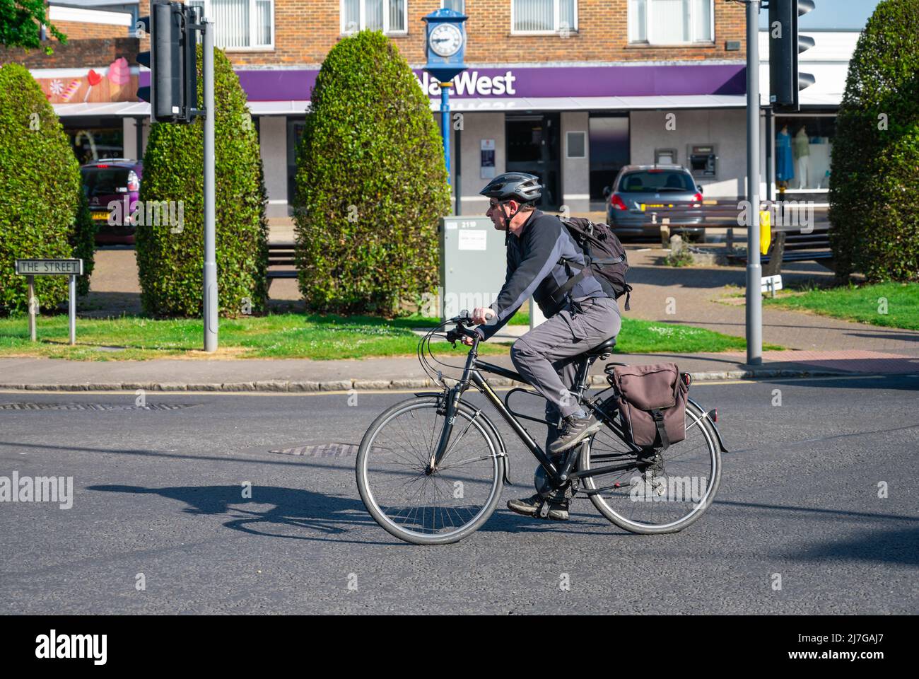 Hombre ciclista en bicicleta en una carretera con casco en primavera en Inglaterra, Reino Unido. Foto de stock