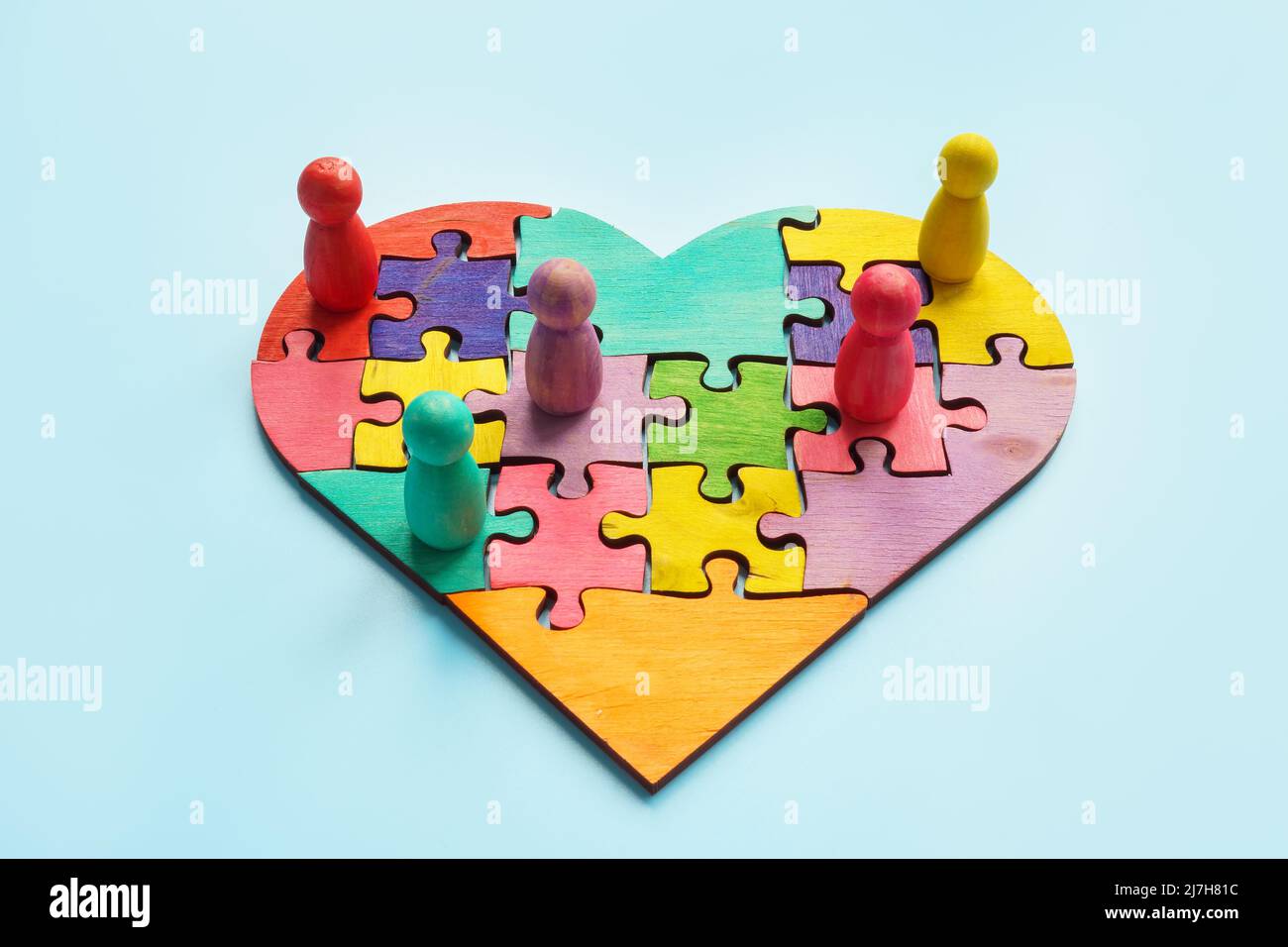 La unión y la inclusión. Corazón de rompecabezas y figuras de colores. Foto de stock