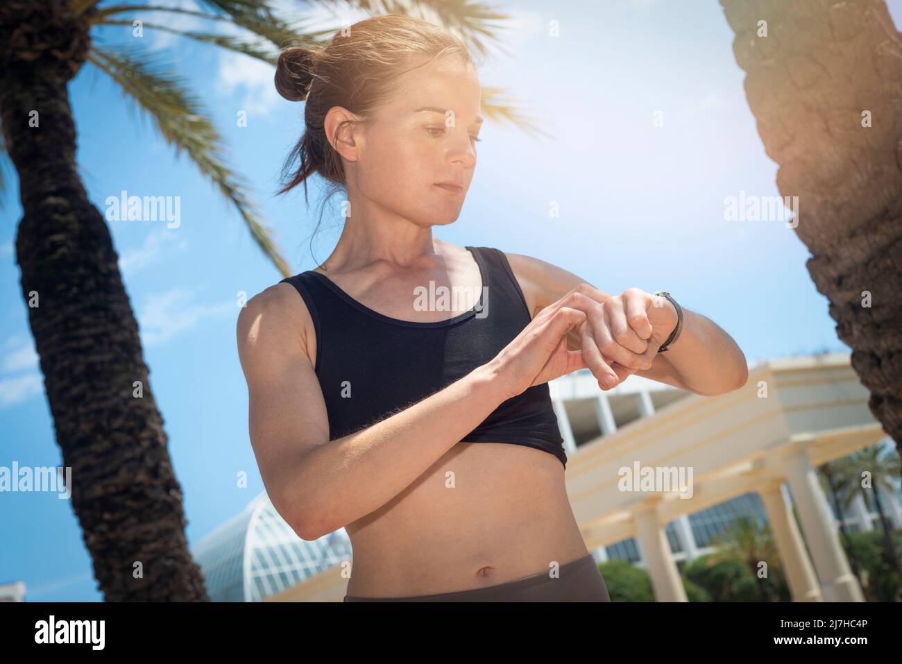 Después de la sesión de entrenamiento Fitness mujer comprueba los resultados sobre smartwatch en fitness app. Concepto de estilo de vida saludable. Atleta Femenina vistiendo sport tracker muñeca Foto de stock