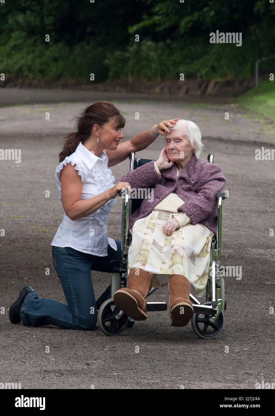 mujer con una señora muy vieja en silla de ruedas Foto de stock