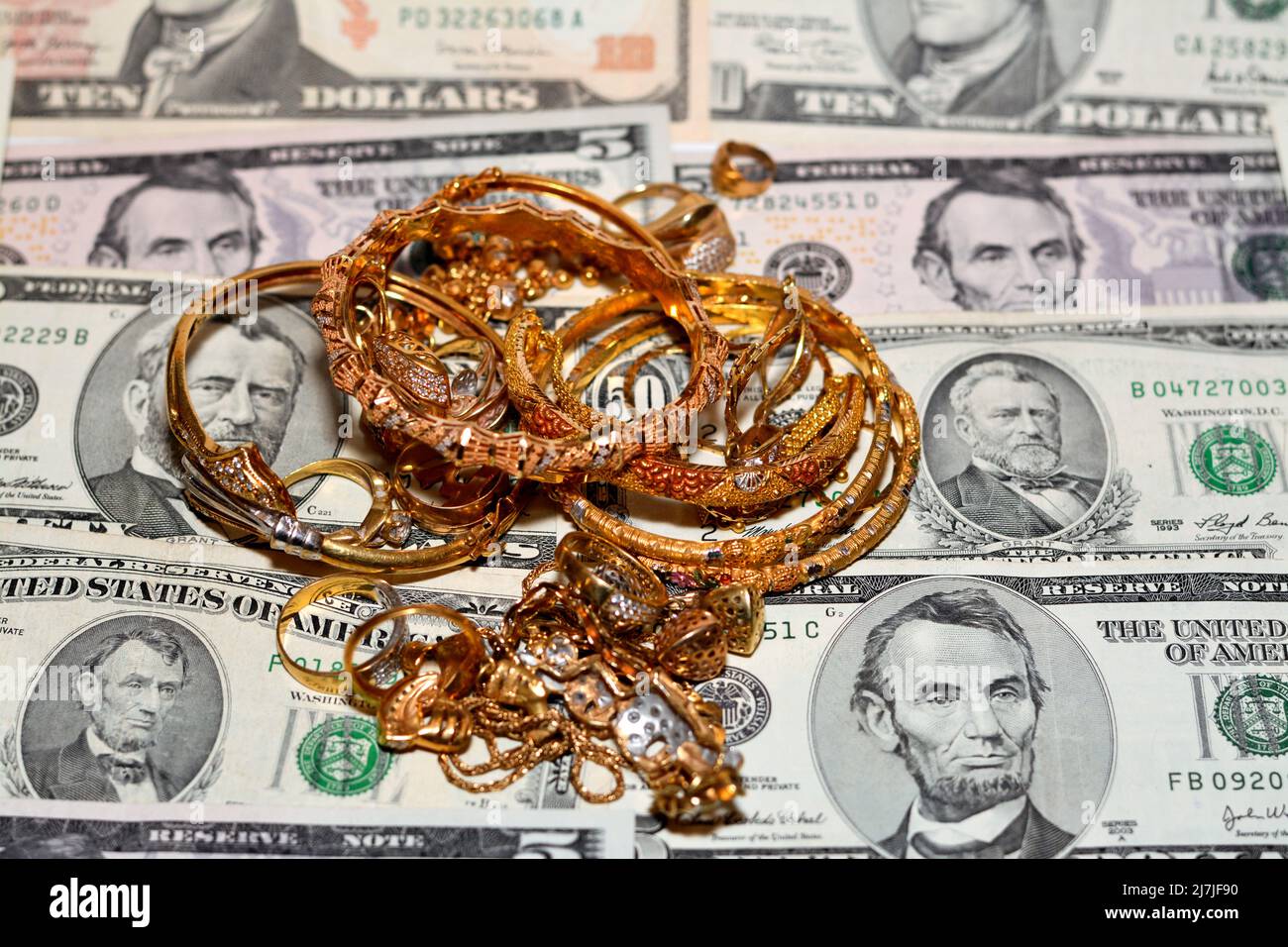 Un conjunto de accesorios de oro de anillos, cadenas pulseras en dólares americanos billetes de diferentes valores, concepto de valor de comprador de joyas, p Fotografía stock -