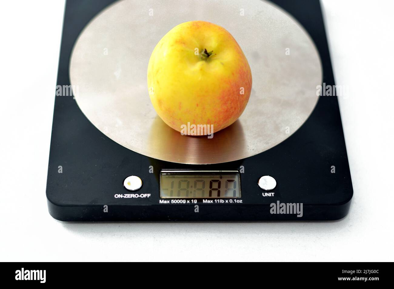 Pesando una fruta de manzana en una báscula de cocina digital en gramos