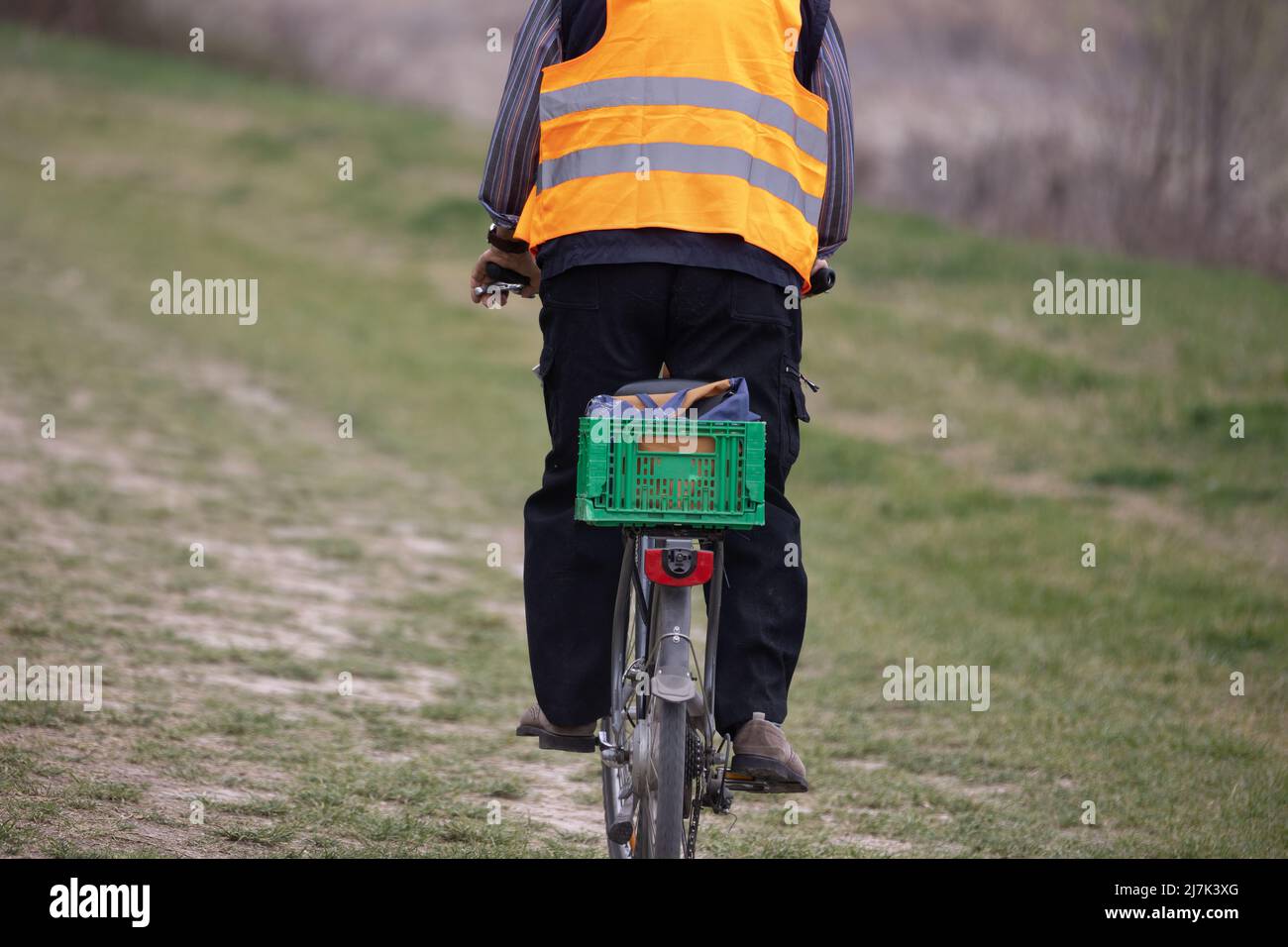 Vista desde detrás de un hombre en una bicicleta con una chaqueta  reflectante y una cesta verde detrás como portaequipajes Fotografía de  stock - Alamy