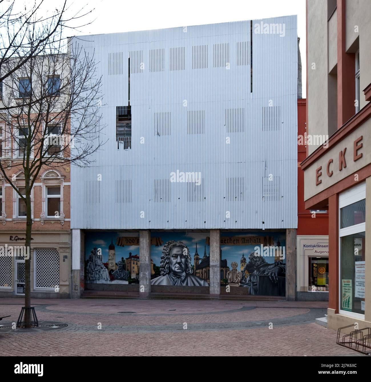 Köthen Anhalt Schalaunische Straße leerstehendes Geschäftshaus mit beschädigter Fassadenverkleidung 74581 darunter moderne Wandmalerei mit stadtgesch Foto de stock