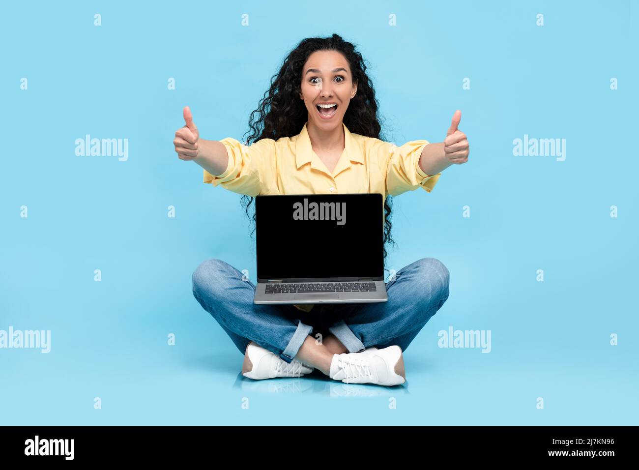 Mujer feliz mostrando una pantalla negra vacía de portátil que se muestra como Foto de stock