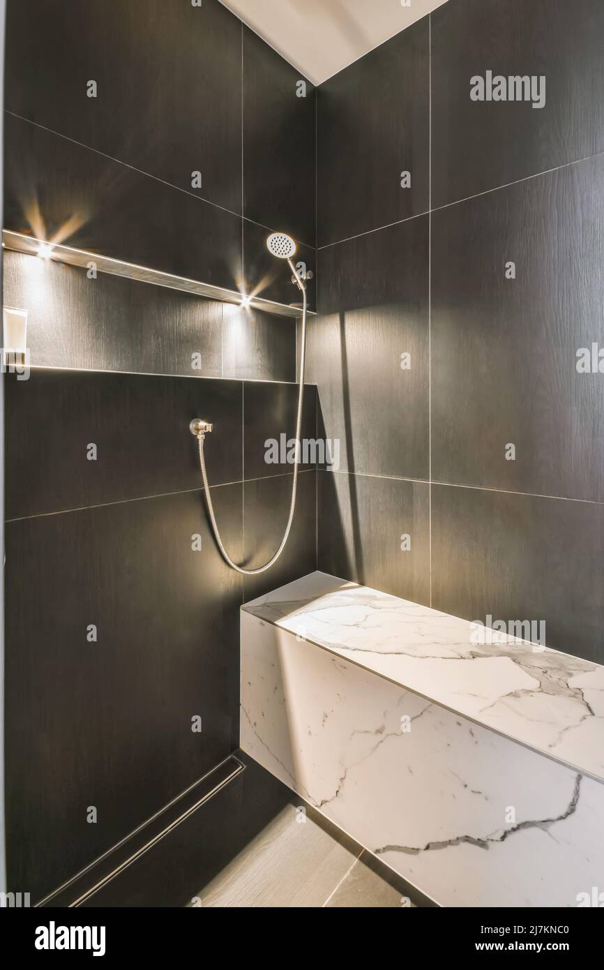 Asiento de mármol en cabina de ducha espaciosa con paredes de azulejos  negros y estante en baño moderno en estilo minimalista Fotografía de stock  - Alamy