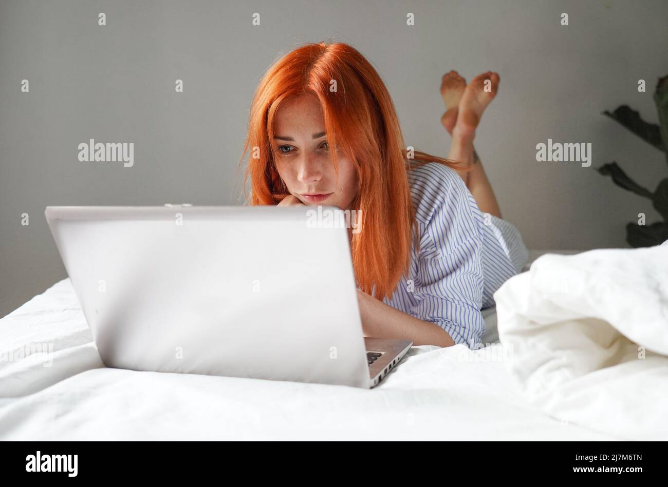 Mujer joven tumbado en la cama con ordenador portátil Foto de stock