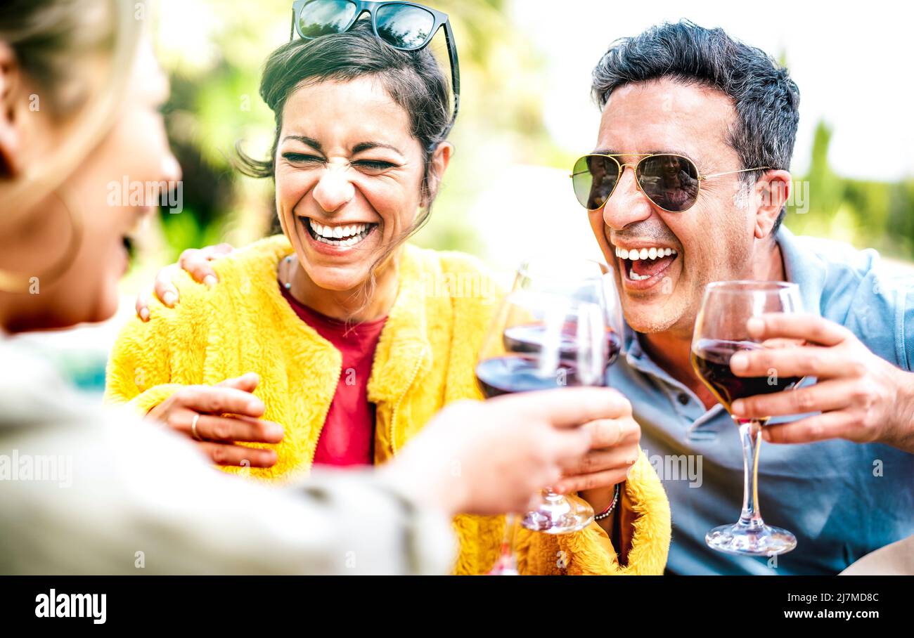 Amigos genuinos bebiendo vino tinto en casa Pic nic Party - Gente de rango de edad mixta divirtiéndose juntos en el bar de la bodega del restaurante en la hora feliz Foto de stock