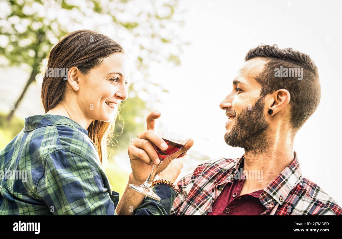 Feliz pareja joven bebiendo vino tinto en la granja de viñedos - Hombre joven mirando los ojos de la mujer hermosa - concepto de la relación de la gente con novio y Foto de stock