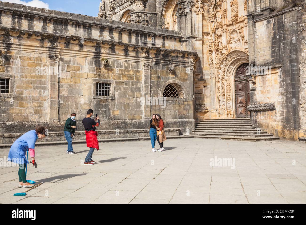 La gente toma fotos delante del mundialmente famoso castillo del monasterio de Tomar con una mujer de limpieza delante Foto de stock