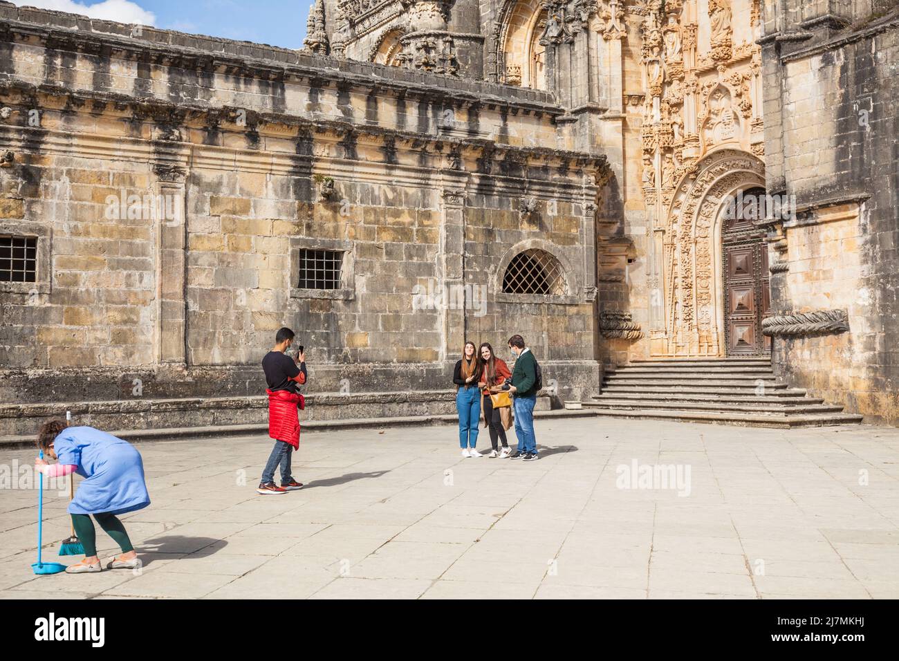 La gente toma fotos delante del mundialmente famoso castillo del monasterio de Tomar con una mujer de limpieza delante Foto de stock