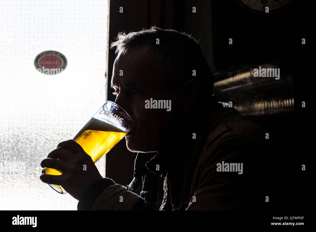 Hombre bebiendo una pinta de cerveza o lager en un bar en Irlanda. Foto de stock