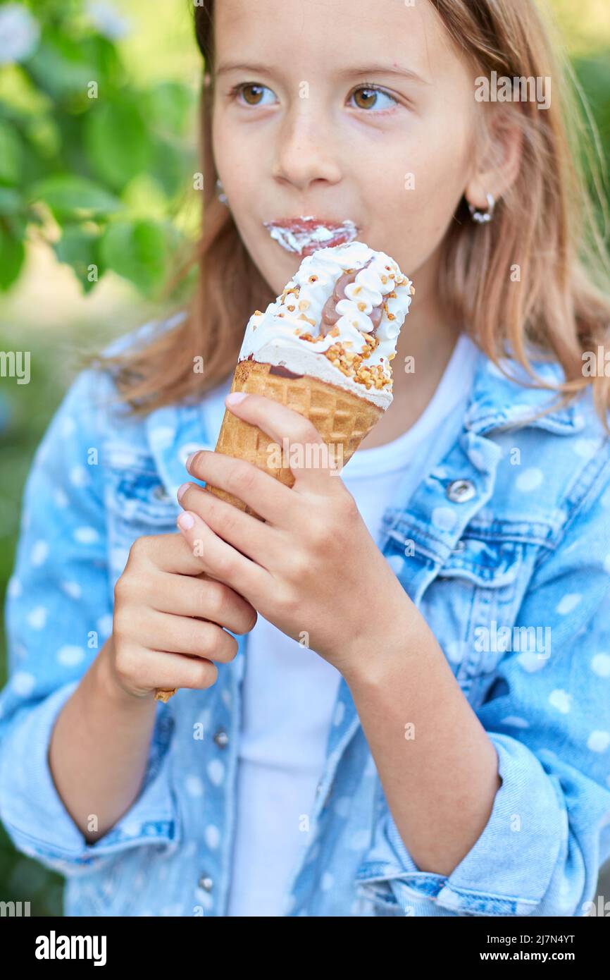 Una chica linda regando y comiendo helado italiano cono mientras descansaba  en el parque el día de verano Fotografía de stock - Alamy