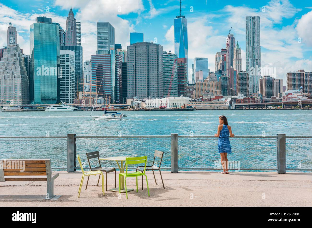 Ciudad de Nueva York El horizonte de Manhattan visto desde el puerto de Brooklyn - mujer disfrutando de la vista. Gente americana caminando disfrutando de la vista de Manhattan sobre el Foto de stock