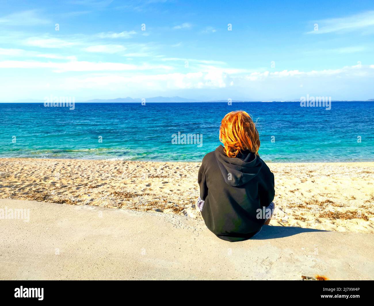 Un niño mira fijamente al mar en Grecia Foto de stock