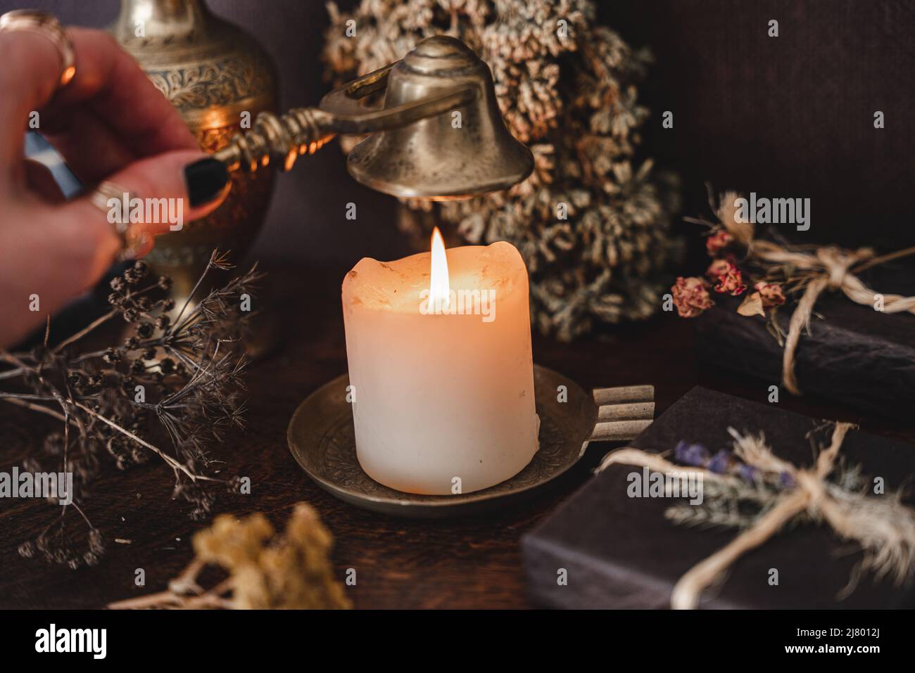 Wiccan bruja poniendo una llama de vela blanca con el snuffer antiguo de  bronce de color dorado mecha. Lanzar un hechizo en el altar de una bruja  Fotografía de stock - Alamy