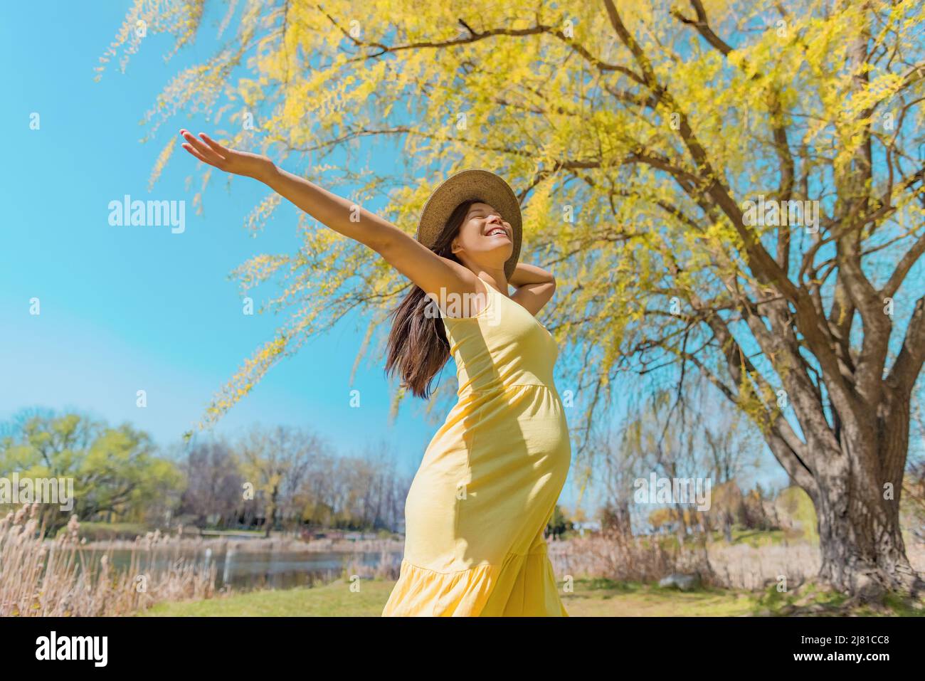 Mujer embarazada feliz bailando despreocupada en la naturaleza de primavera con los brazos abiertos. Asia niña felicidad gratis saludable verano al aire libre embarazo Foto de stock