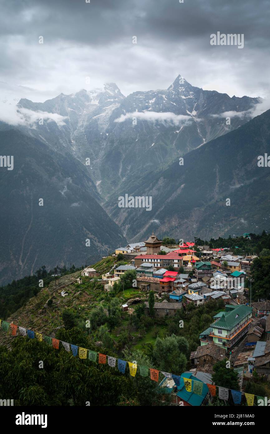 Vista elevada de las montañas del Himalaya con pendientes pronunciadas y algunos bosques. Kalpa, India. Enmalle con edificios tradicionales dominados por altos picos nevados. Foto de stock