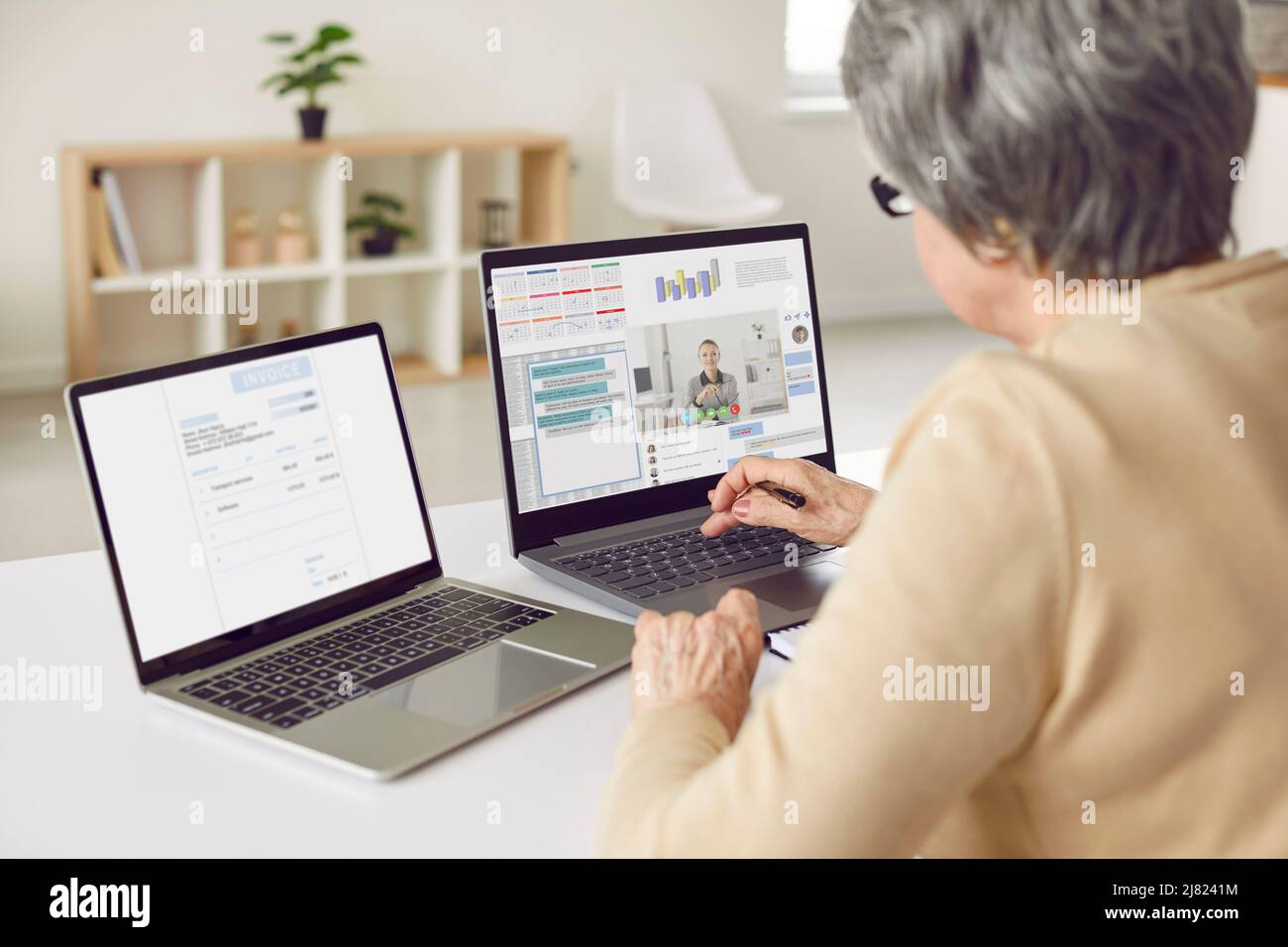 Mujer tomando consultas empresariales en línea y utilizando varias aplicaciones en dos ordenadores portátiles Foto de stock
