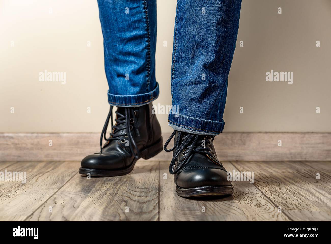 Hombre con botas de cuero negro y jeans en un suelo de madera Fotografía de  stock - Alamy