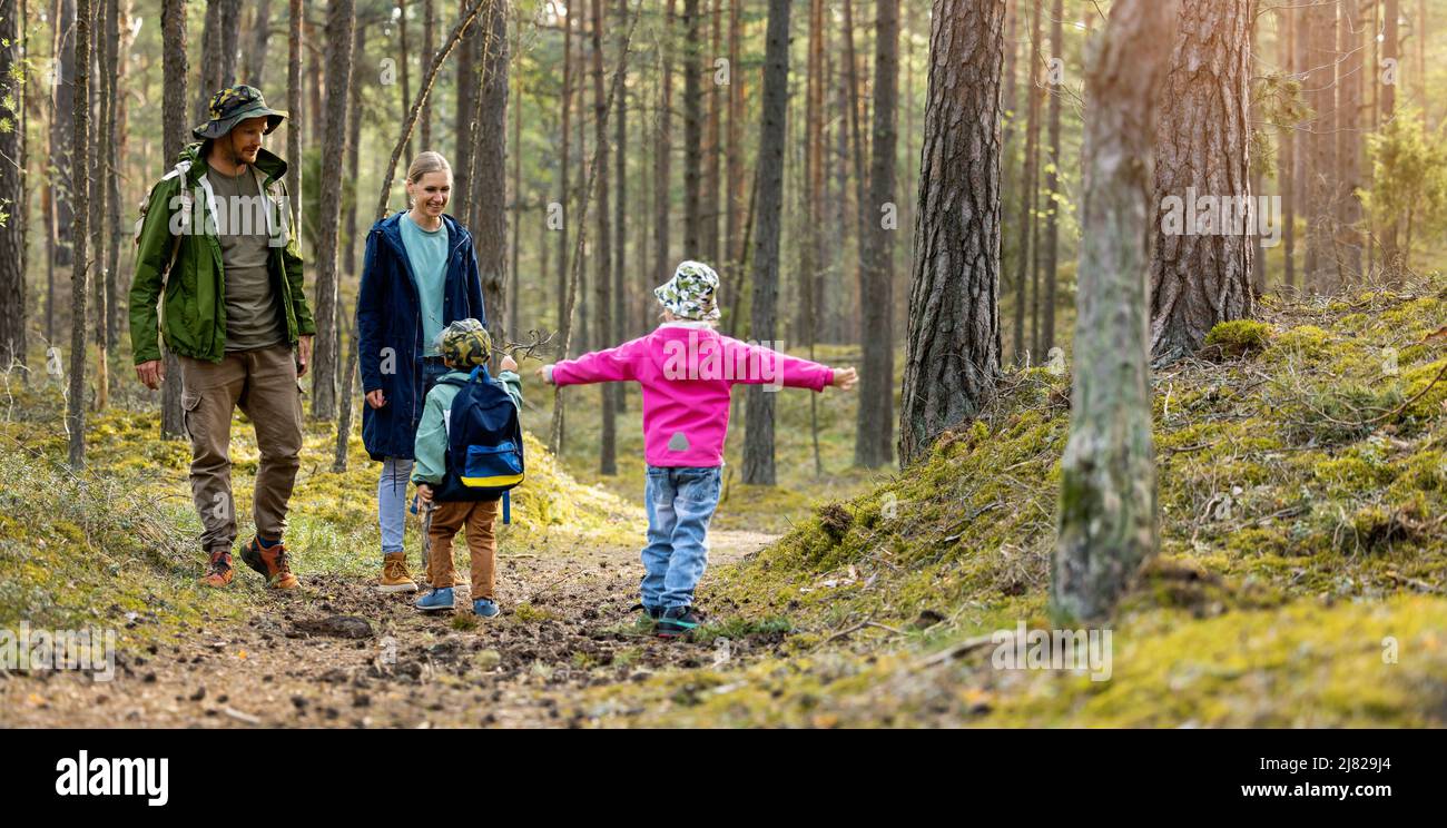 una familia joven y activa con dos niños pasa tiempo juntos en un paseo por el bosque. espacio de copia Foto de stock