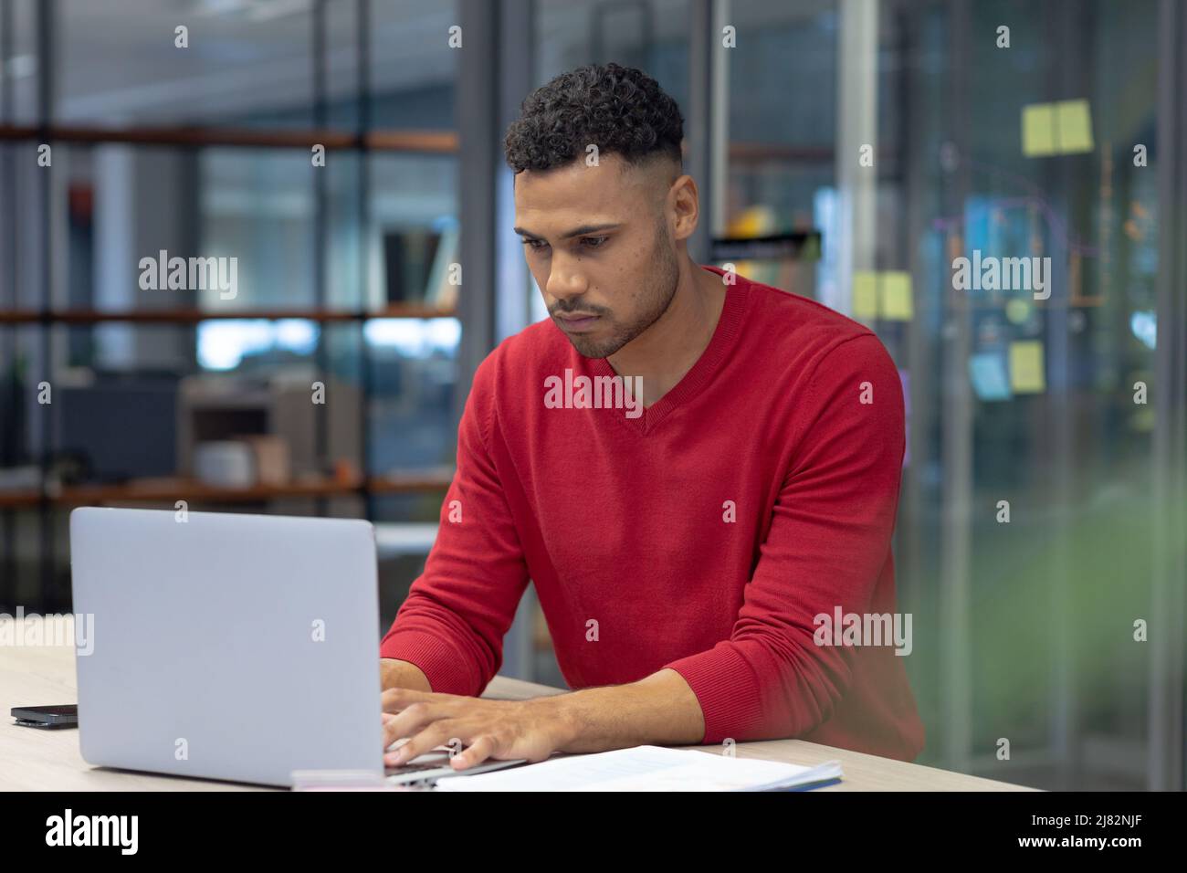 Consejero masculino hispano confiado que utiliza el portátil mientras que trabaja en el lugar de trabajo moderno Foto de stock