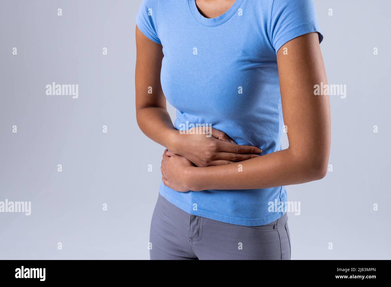 Sección media de una mujer afroamericana de mediana edad con dolor de estómago sobre fondo blanco, espacio de copia Foto de stock