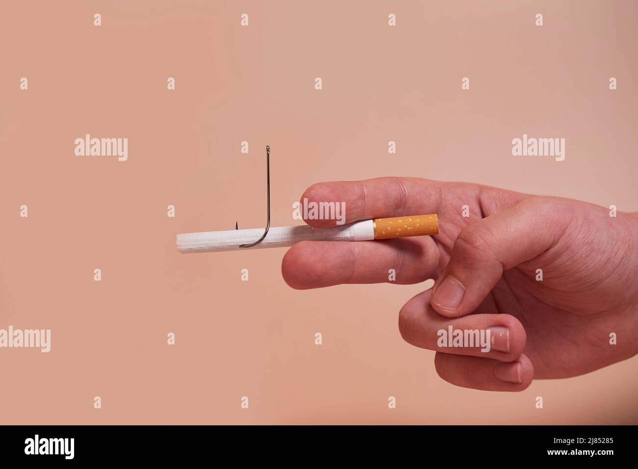 La mano de un niño sostiene un cigarrillo con un anzuelo Foto de stock