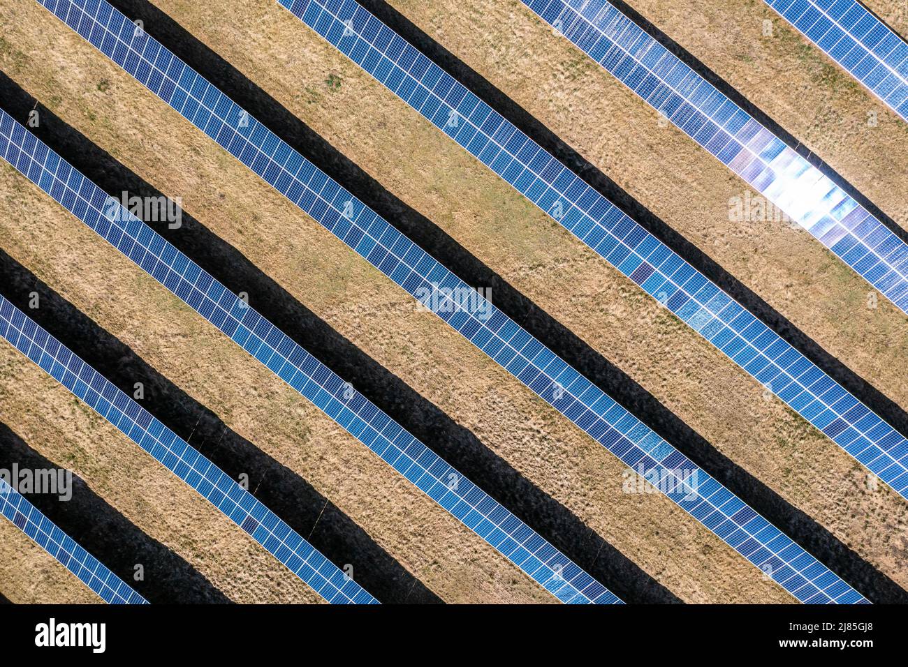 Vista aérea de la granja solar, filas de paneles fotovoltaicos por una pequeña casa Foto de stock