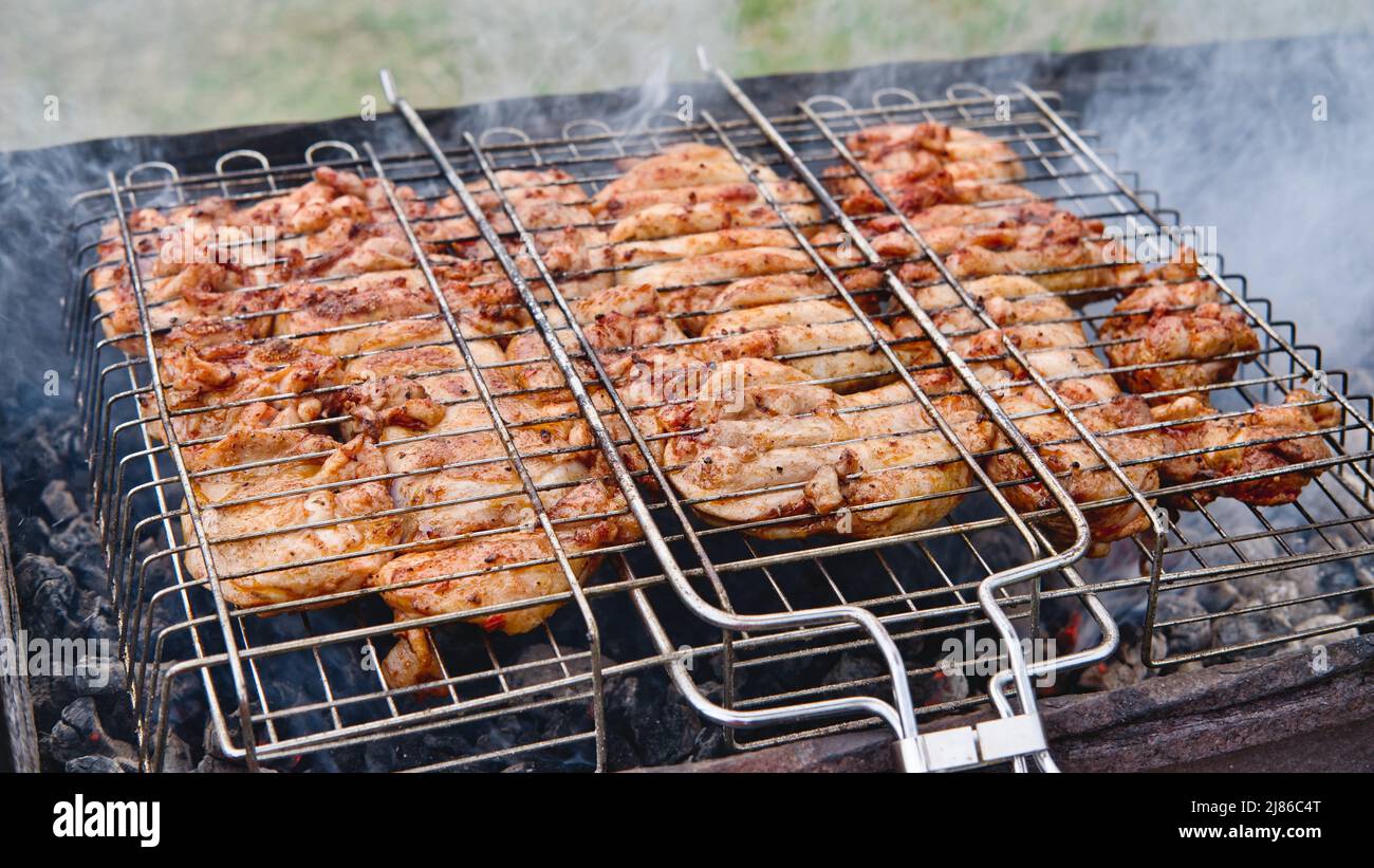 Cocinar carne de pollo al aire libre en el momento del picnic con parrilla. Barbacoa de carne de pollo a la parrilla. Foto de stock