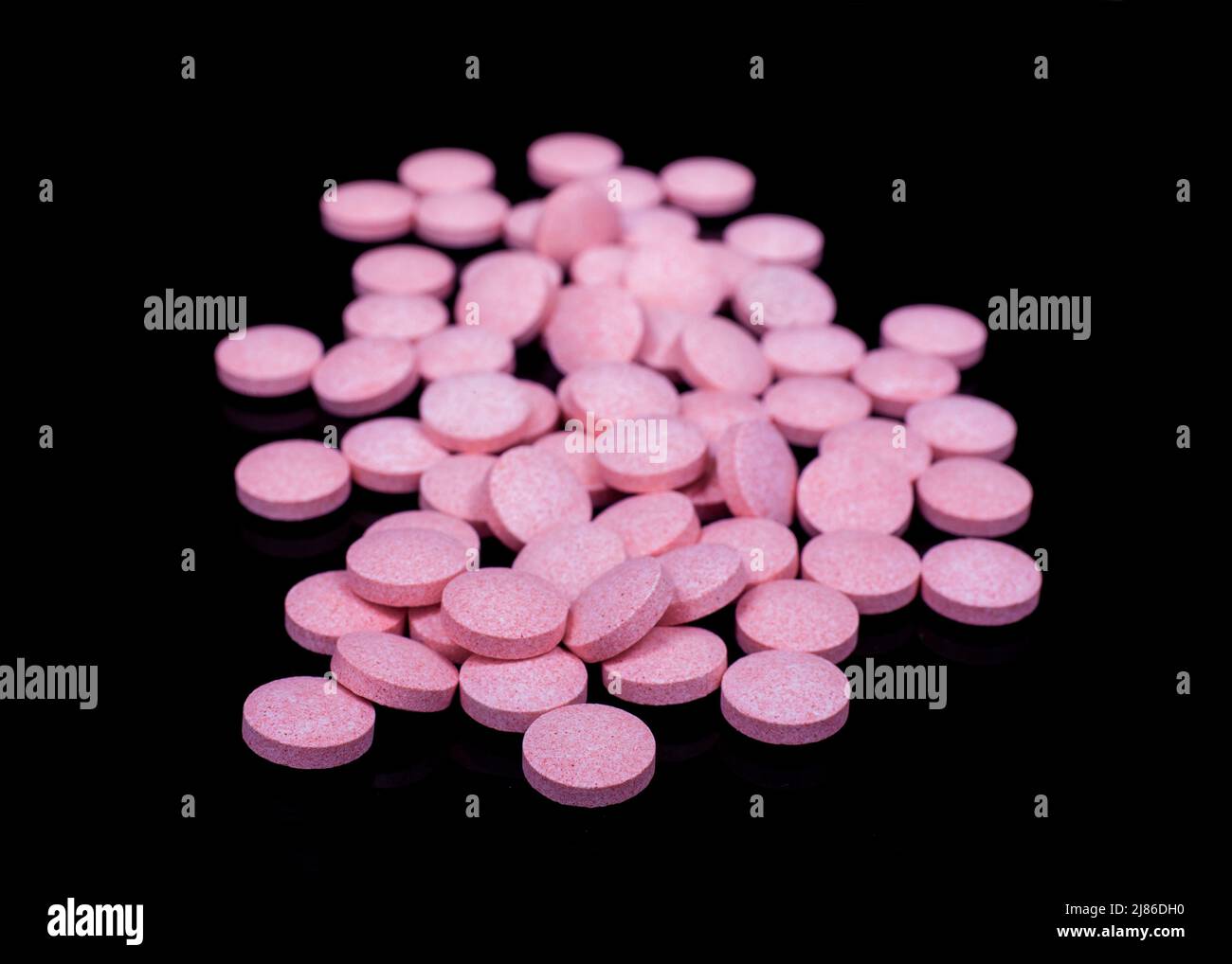 Pastillas rosadas en la superficie negra reflectante Foto de stock