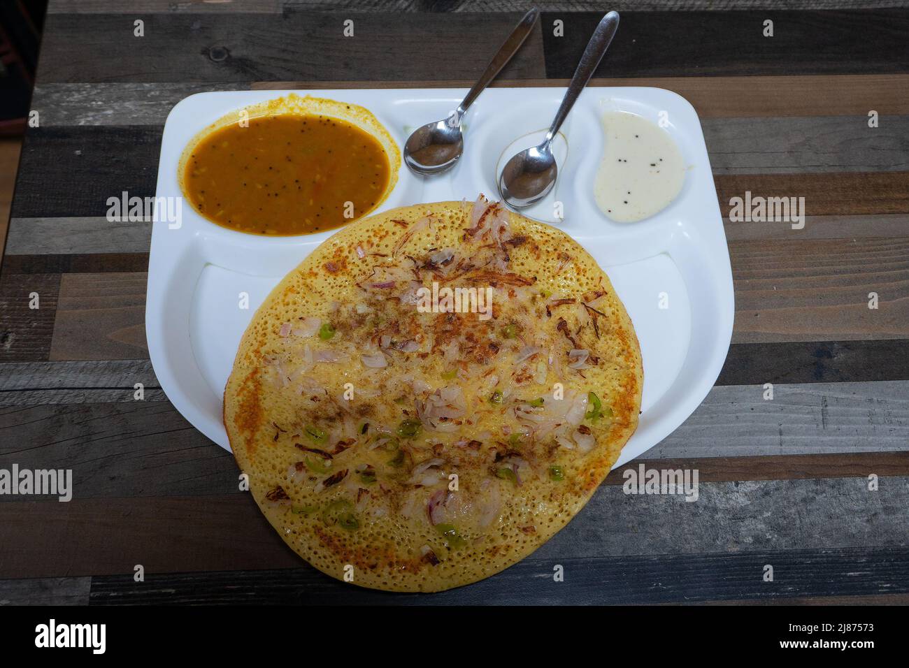 Uttapam se sirve con chutney en plato blanco, plato de verduras indias. Foto de stock