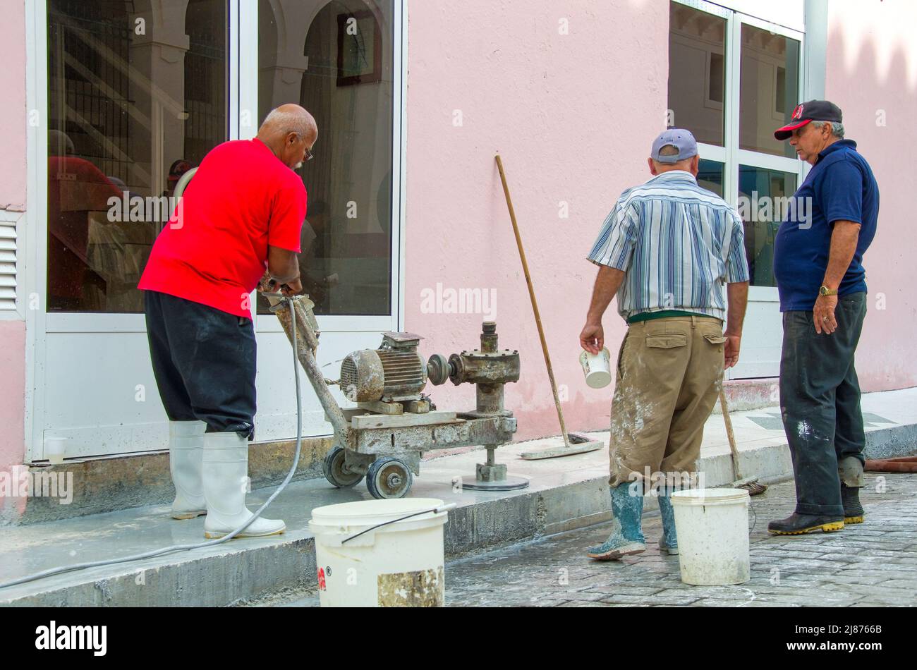 Un cubano afrocaribeño opera un equipo de pulido rústico y casero. Está puliendo la acera de granito en la nueva oficina de viajes de El Ra Foto de stock