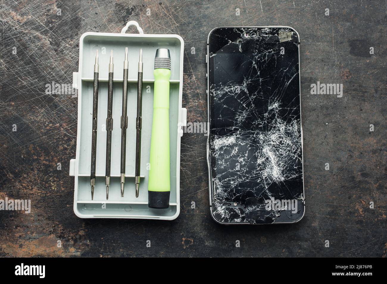 Smartphone con una pantalla rota y herramientas de reparación sobre el fondo grunge. Primer plano. Foto de stock